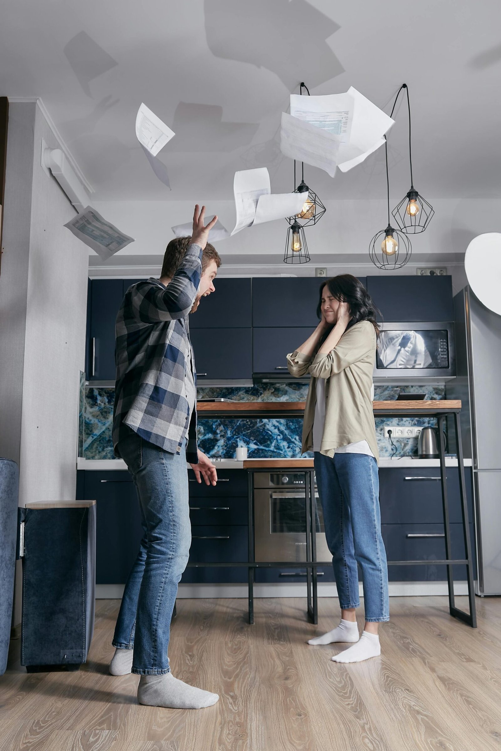 A dramatic scene of a young couple in a heated argument with papers flying in the air.