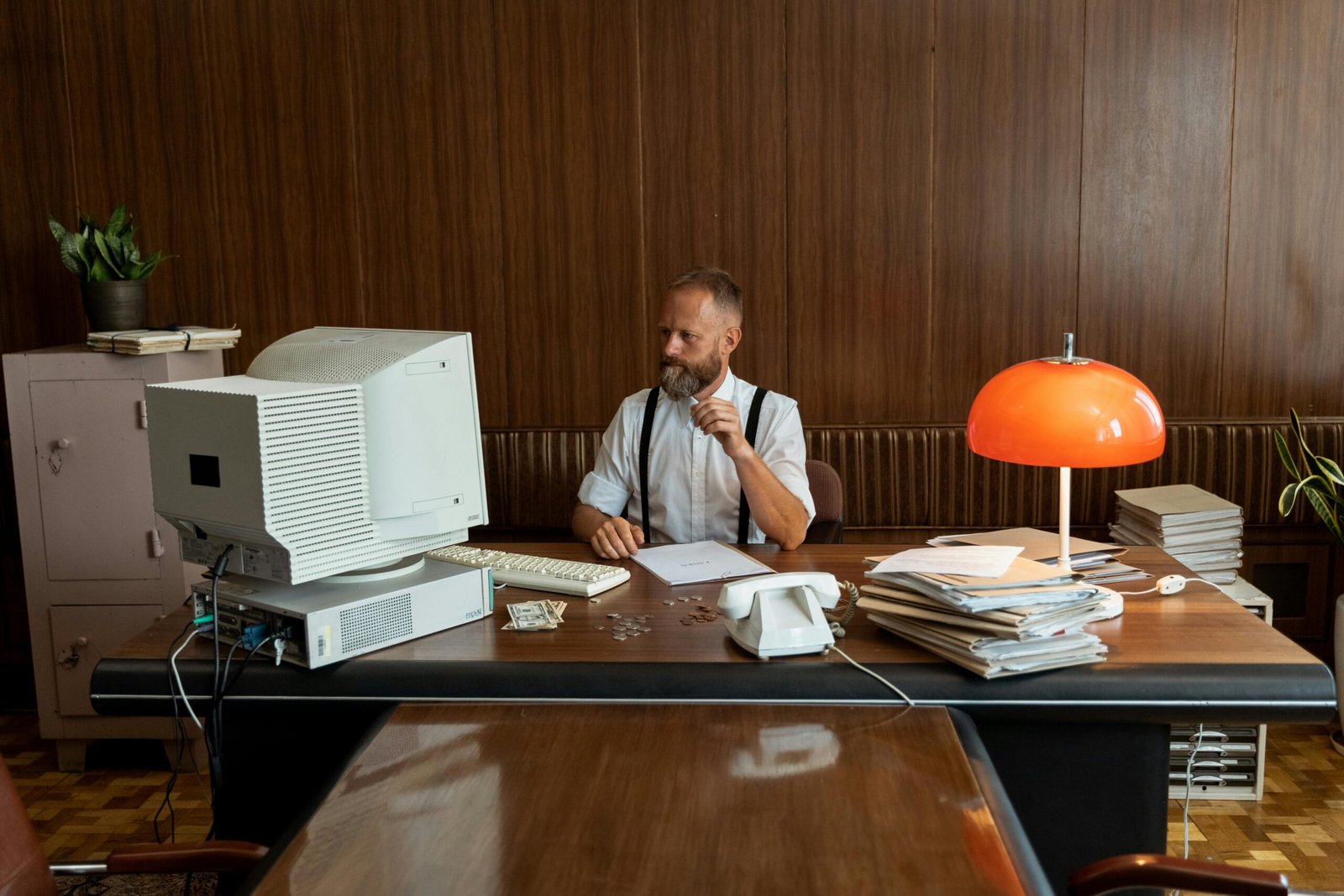 Man in vintage office setting with retro computer and decor, embodying 80s business vibe.